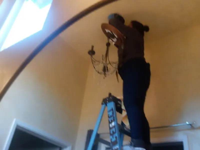 Electrician installing a chandelier in a Harlan residence